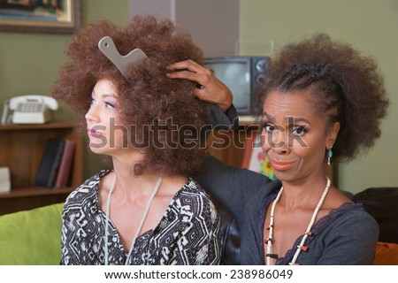 White woman with afro wig and unimpressed friend