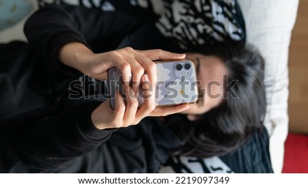 White woman checking the phone, lying in the sofa, no face, horizontal view