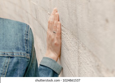 White woman hand touches the wall. Closeup of religion fingers on the stone ancient street wall. Ritual and feelings of prayer person beside the exterior construction