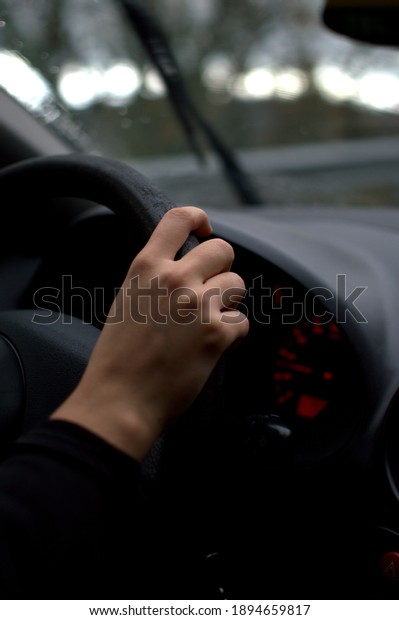 White woman hands in car on rainy autumn or winter\
day driving on the road
