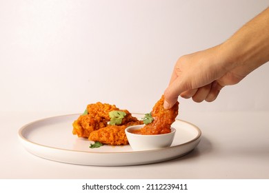 White Woman Holding Buffalo Wing In Her Hand And Filling It With Red Hot Sauce