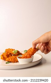 White Woman Holding Buffalo Wing In Her Hand And Filling It With Red Hot Sauce