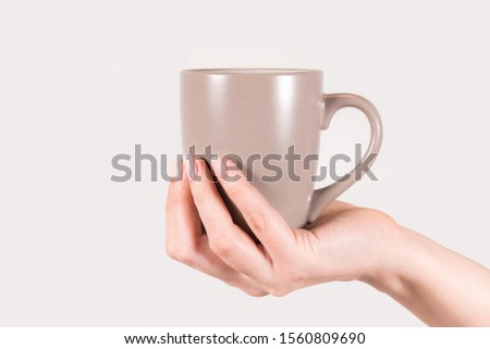 White woman with manicured fingernails holding cup in one hands. Horizontal color photography.