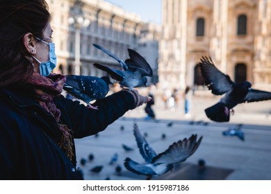 white woman playing with the birds of the cathedral of milano, duomo of milan, pigeons of square