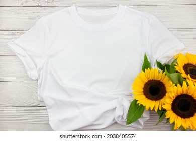 White Womens Cotton T Shirt Mockup With Sunflowers On White Wooden Background. Design T Shirt Template, Print Presentation Mock Up. Top View Flat Lay.