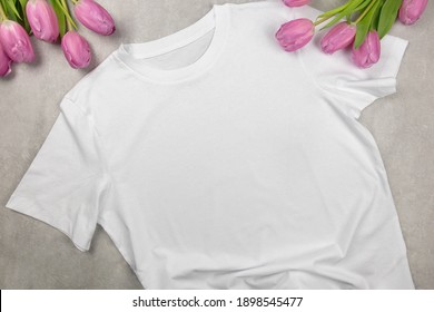 White Womens Cotton Tshirt Mockup With Pink Tulips. Design T Shirt Template, Print Presentation Mock Up. Top View Flat Lay. Concrete Stone Background.