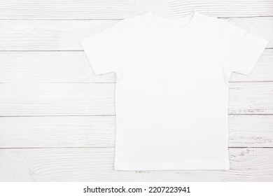 White Womens Cotton Tshirt Mockup On Wooden Background. Design T Shirt Template, Print Presentation Mock Up. Top View Flat Lay. 