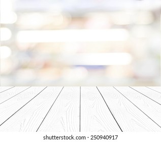 White Wood Background Table For Product Display, Empty Perspective White Wooden Tabletop, Counter And Blurred Store With Abstract Bokeh Light Background, Mock Up, Template Banner, Backdrop, Poster