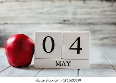 White wood calendar blocks with the date May 4th and a red apple for National Teacher Appreciation Day. 