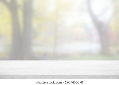 Weißer Holztisch mit unscharfem Garten im Herbsthintergrund.