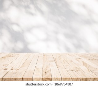 White wood table top with shadow of tree leaf on wall background.For product display and natural concept