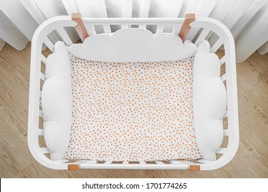 White wooden baby crib with pillows shaped clouds  in baby's room. Top view of child's bed