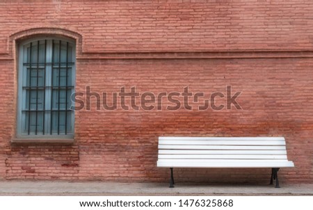 White wooden bench with a wall behind salmon brick and blue cyan blue wooden window, vintage style. Background for your photographs