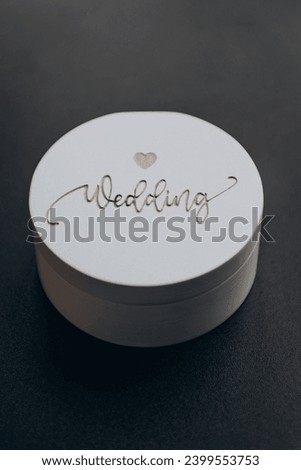 A white wooden box for the wedding rings of the bride and groom lies on a golden canvas. Wedding, holiday.
