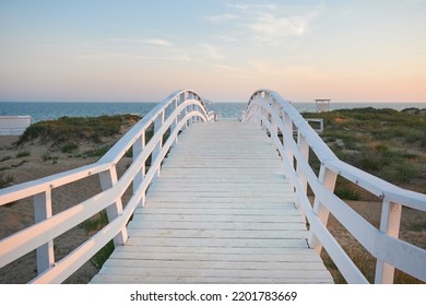 White Wooden Bridge On The Beach At Sunset