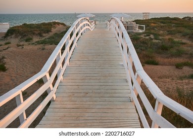 White Wooden Bridge On The Beach At Sunset