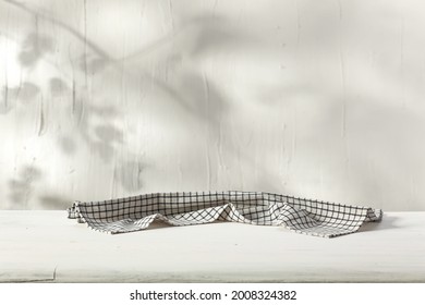 White wooden desk of free space and wall with shadows. White and black napkin decoration 