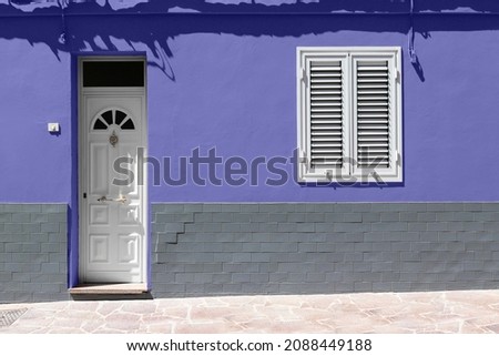 White wooden front door and white window on very peri wall with gray brick.