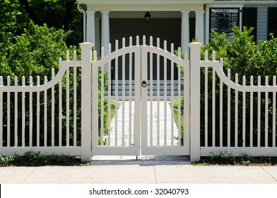 White wooden gate and picket fence on elegant home entrance