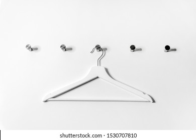 White wooden hanger hanging on a hook on a white wall
