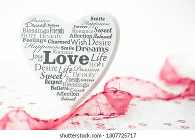 White Wooden Heart With Different English Words Concerning Love And Red Ribbon And Heart Confetti On White Grey Wooden Underground