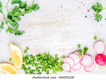 White Wooden Kitchen Table Background With Healthy Cooking Ingredients And Copy Space. Vegetables And Herbs For Salad. Radish, Spring Onion, Parsley, Lemon. Top View