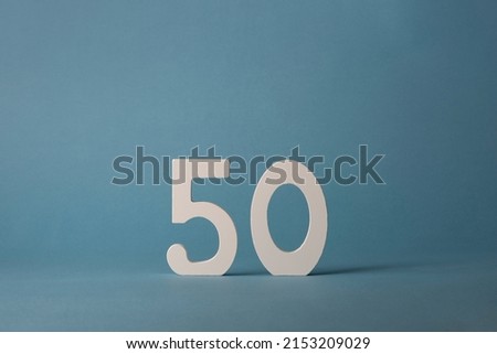 White wooden number fifty 50 on blue background.