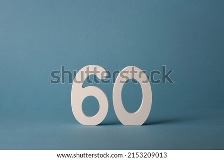 White wooden number sixty 60 on blue background.
