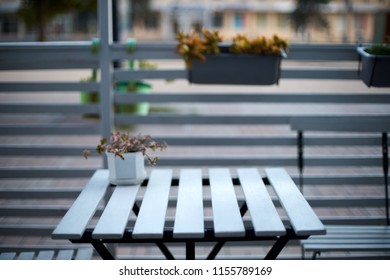 White Wooden Planks Table, Chairs And Horizontal Fence Of Cafe In The Street. Blur Background For Product Placement. Isolated Outdoor Empty European Restaurant Or Coffee Shop Exterior. No People.