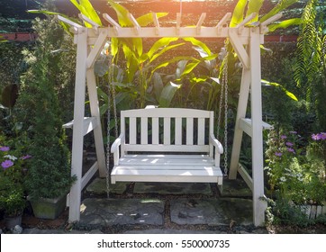 White Wooden Porch Swing In Garden