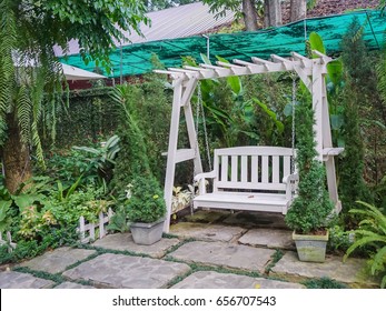 White Wooden Porch Swing In Garden