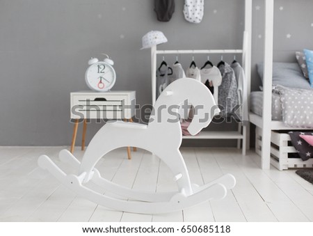 White wooden rocking horse in stylish modern children room.  Unisex gender neutral room