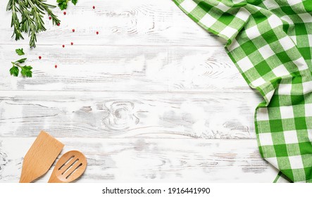 White wooden table covered with green tablecloth and cooking utensils. View from top. Empty tablecloth for product montage. Free space for your text