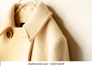 White Wool Coat Hanging On Clothes Hanger On White Background.Close Up