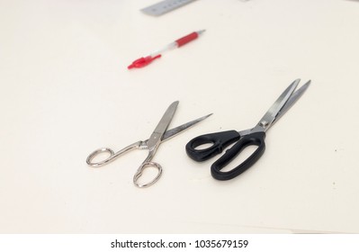 White working table of tailor with tools, pair of scissors and pen