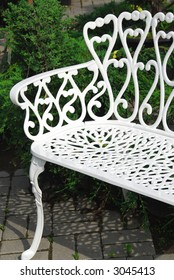 White Wrought Iron Bench In A Garden