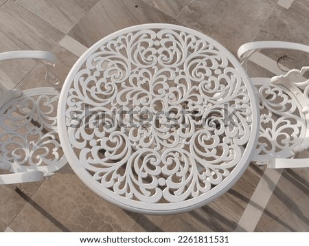 white wrought iron table and chair with floral motifs on terrace at dawn. High quality photo