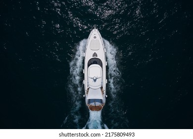 White Yacht On The Sea Aerial View. Superyacht Is Moving Fast On The Water Top View. Motor Yacht In Motion Top View. A Huge Super Mega Yacht In White On Dark Blue Water In Italy.