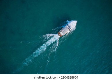 White Yacht On The Water Top View. White Boat On Blue Water Aerial View. Boat In Motion Top View.