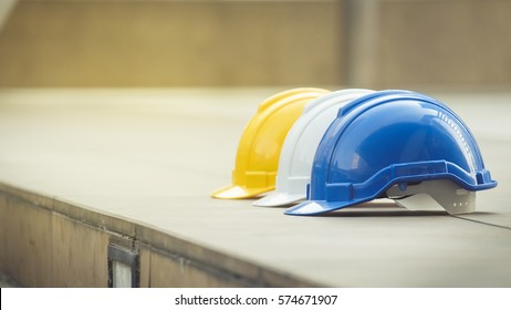 white, yellow and blue hard safety helmet hat for safety project of workman as engineer or worker, on concrete floor on city - Shutterstock ID 574671907