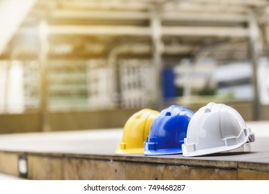 white, yellow and blue hard safety helmet hat for safety project of workman as engineer or worker, on concrete floor on city. - Shutterstock ID 749468287