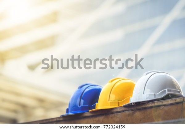 white, yellow and blue hard safety helmet hat for\
safety project of workman as engineer or worker, on concrete floor\
on city.
