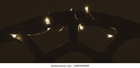 White and yellow fairy lights wrapped around piano music rack glowing in dark room - Powered by Shutterstock