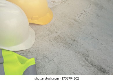 white and yellow hard safety helmet hat for safety project of workman as engineer or worker, on concrete floor. Standard construction safety equipment.