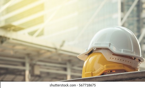 white, yellow hard safety helmet hat for safety project of workman as engineer or worker, on concrete floor on city
