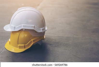 white and yellow hard safety helmet hat for safety project of workman as engineer or worker, on concrete floor on city,Downtown background