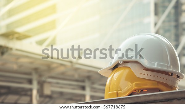 white,\
yellow hard safety helmet hat for safety project of workman as\
engineer or worker, on concrete floor on\
city