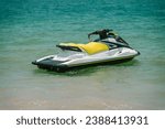 White yellow jetski close to seashore ready to drive, sunny day, tropical water sports.