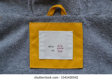  White And Yellow Label On Grey Background. Size 104 Clothes, 3/4 Year. 