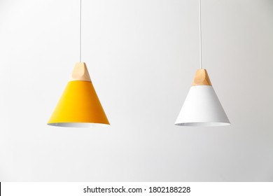 White and yellow lamps with light wooden parts are hanging on the cables
